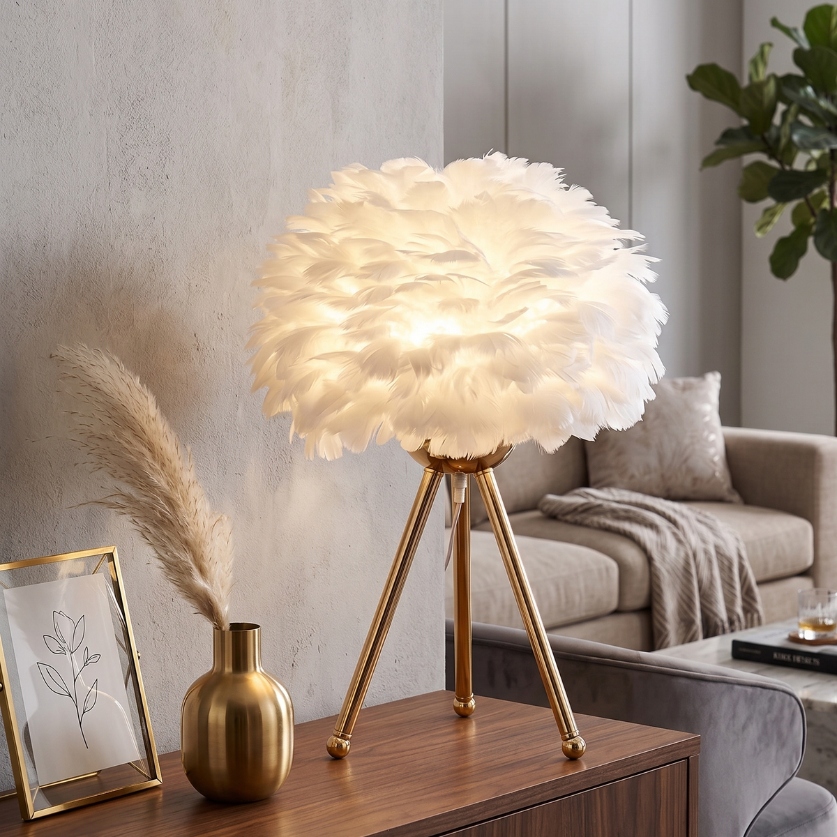 Lampe à poser avec abat-jour en plumes blanches et pied trépied en métal doré, allumée sur un meuble en bois dans un salon cosy aux tons neutres.