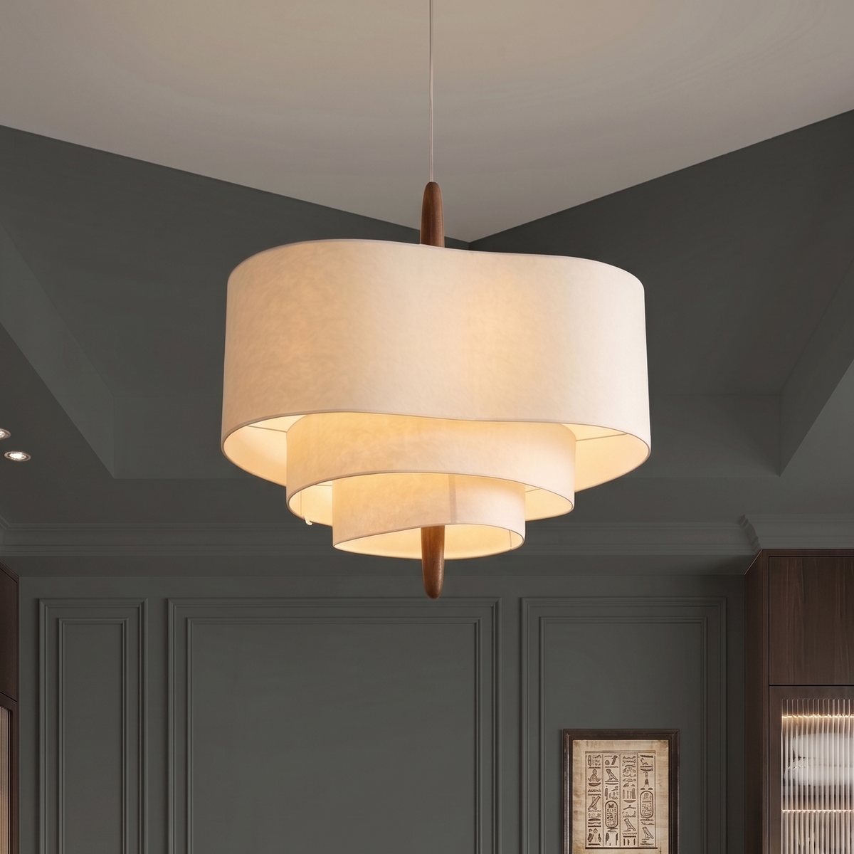 Suspension à abat-jour en tissu blanc cassé sur trois étages décalés, avec finitions en bois foncé, diffusant une lumière chaude dans une pièce aux murs vert sauge moulurés.